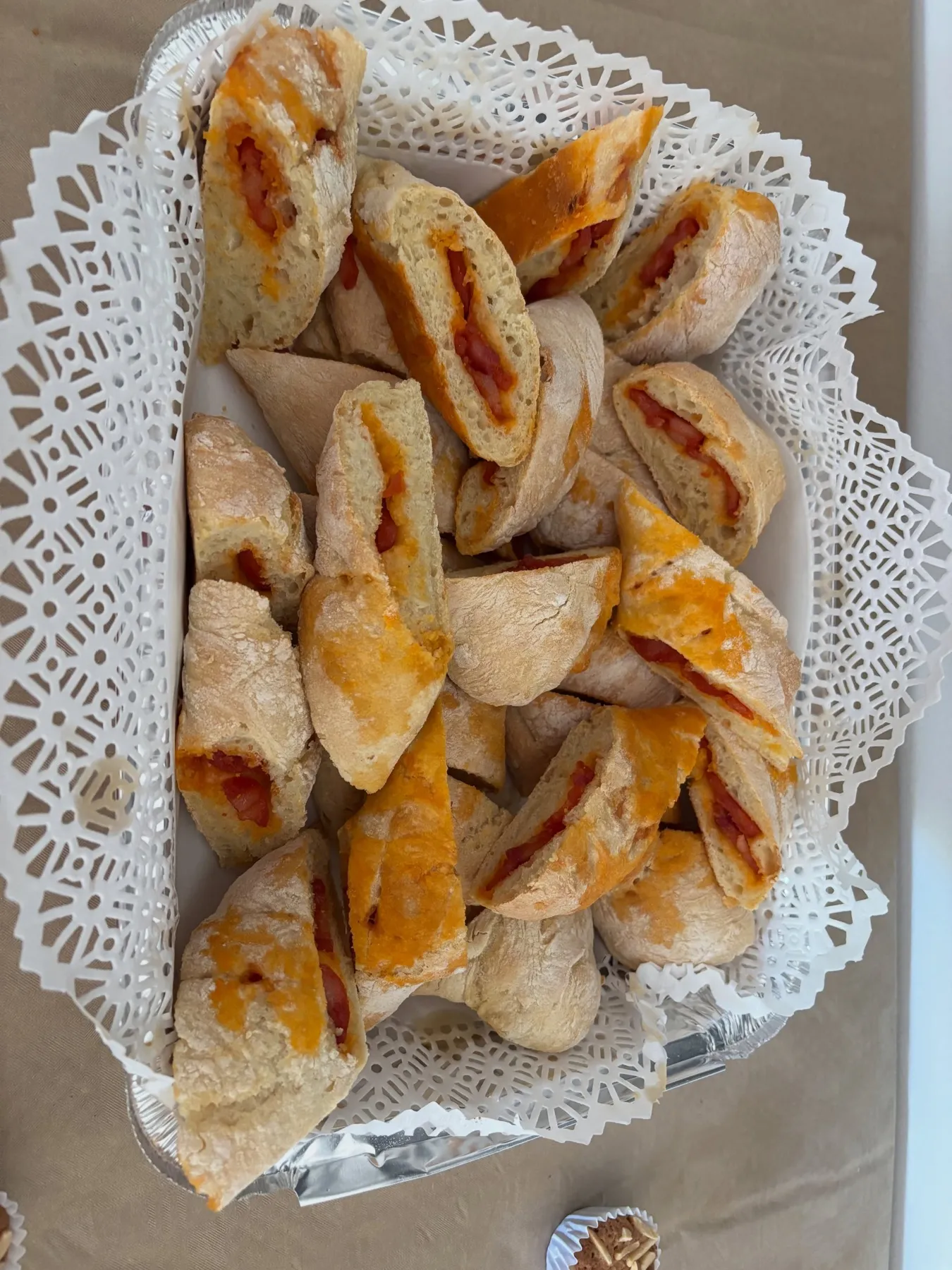 Pão com chouriço cortado às fatias num cesto com naperon